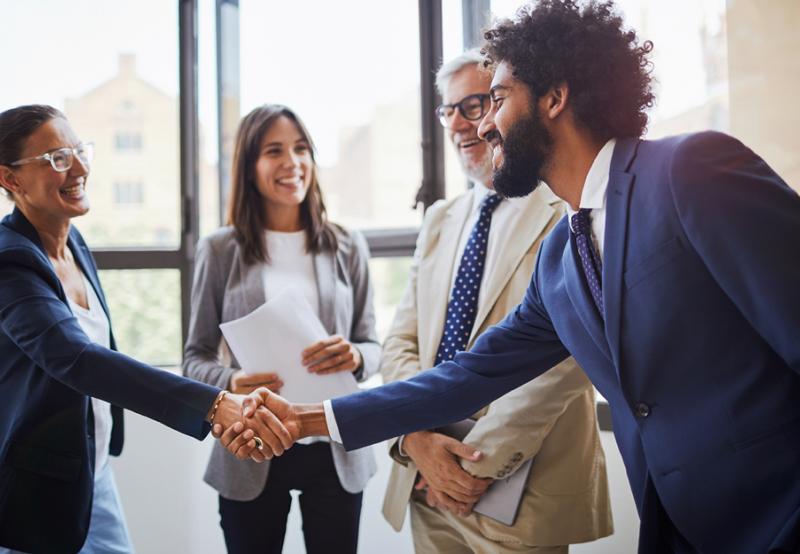 A candidate dressed appropriately for a job interview shaking hands with a recruiter