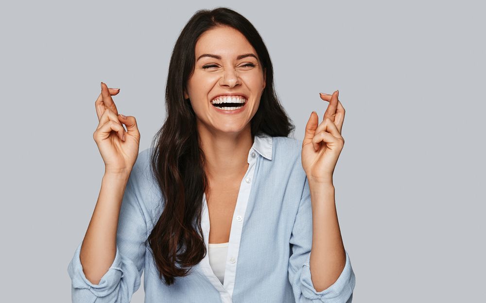 A woman with her fingers crossed finding 8 ways to get luckier when searching for a job interview