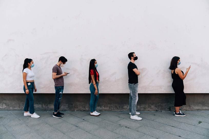 COVID-19 masked retail customers waiting in line and respecting social distancing